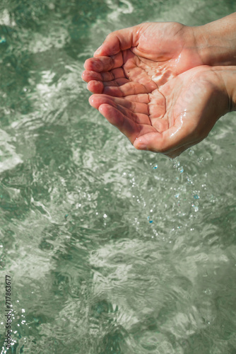Tender touching surface of ocean water. Woman's hand touching surface of turquoise water in sunlight. Nature water concept, woman hand. Woman's hand at clear turquoise water.
