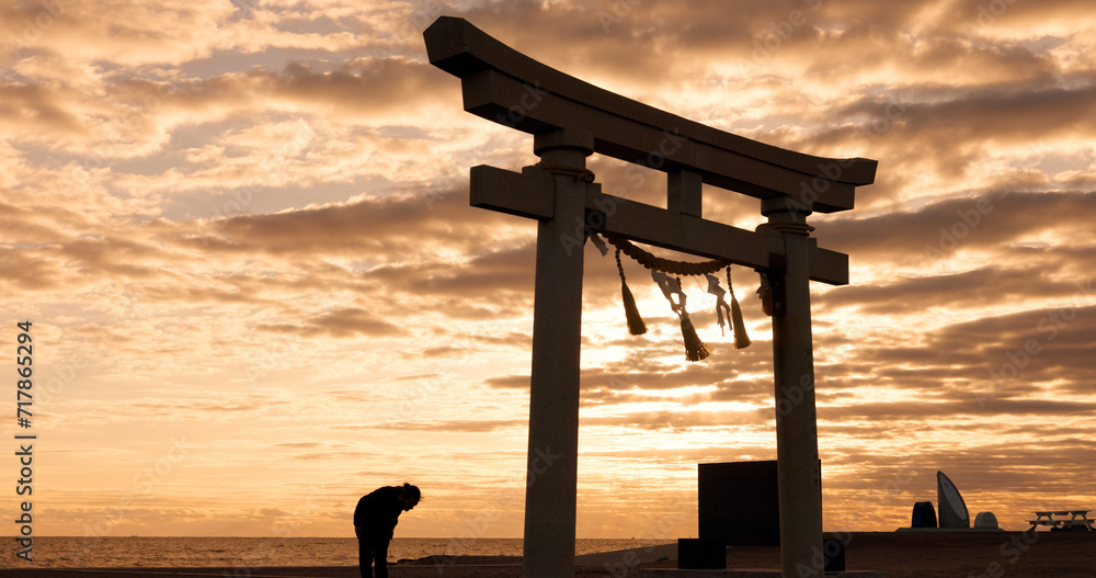 Torii gate, sunset sky in Japan and man in silhouette with clouds, zen and spiritual history on travel adventure. Shinto architecture, Asian night culture and calm nature on Japanese sacred monument.