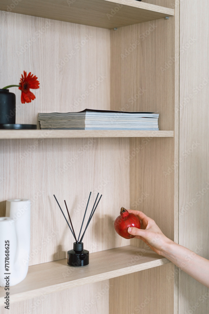 Φωτογραφία Vertical shot of woman hand holding decorative element near wooden shelf of cabi