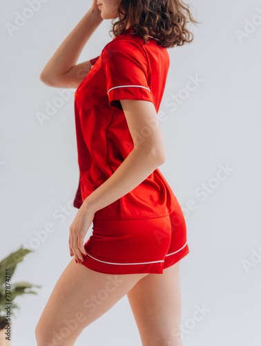 Beautiful curly woman with smile in red stylish sleepwear outfit on a white background
