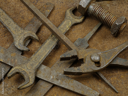 Old rusty instruments open end wrench, pliers, rasp and others lie on the rusty sheets metal 