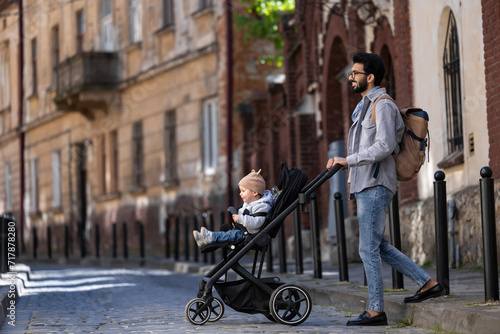 Dark-haired tall man with a baby carriage in the city street