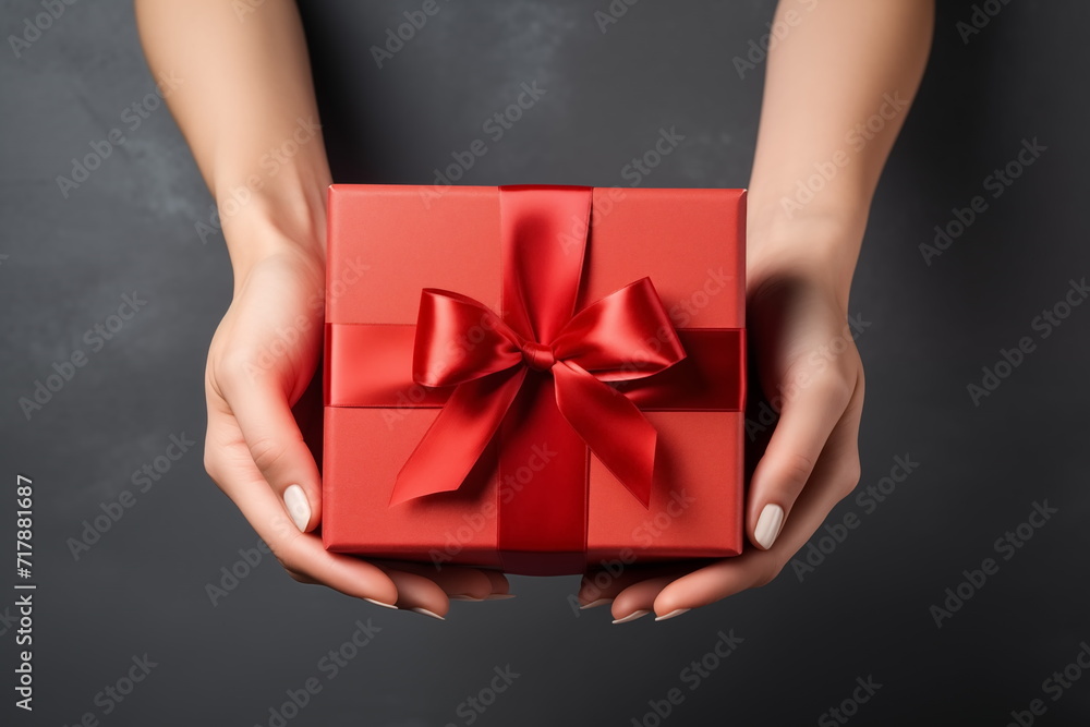 Top view of hands holding craft red paper gift box with ribbon bow on isolated black background. Generated AI. Top view of hands holding craft red paper gift box with ribbon bow on isolated black background. Generated AI.