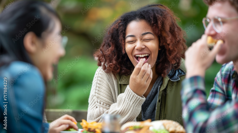 Fototapeta premium young woman with curly red hair is laughing heartily with her friends at an outdoor dining table