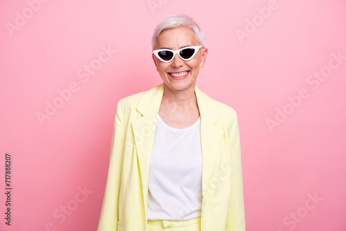Photo portrait of toothy smiling mature lady in yellow jacket cheerful business boss on vacation isolated over pink color background