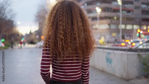 Urban Wanderlust: Confident Young Woman with curly hair Strolling through City Streets.