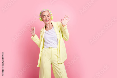 Photo of woman senior age in yellow suit dancing enjoying wireless headphones she bought from aliexpress isolated on pink color background