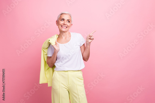 Photo of smiling mature woman took off blazer wear yellow suit direct finger copyspace her marketplace isolated on pink color background
