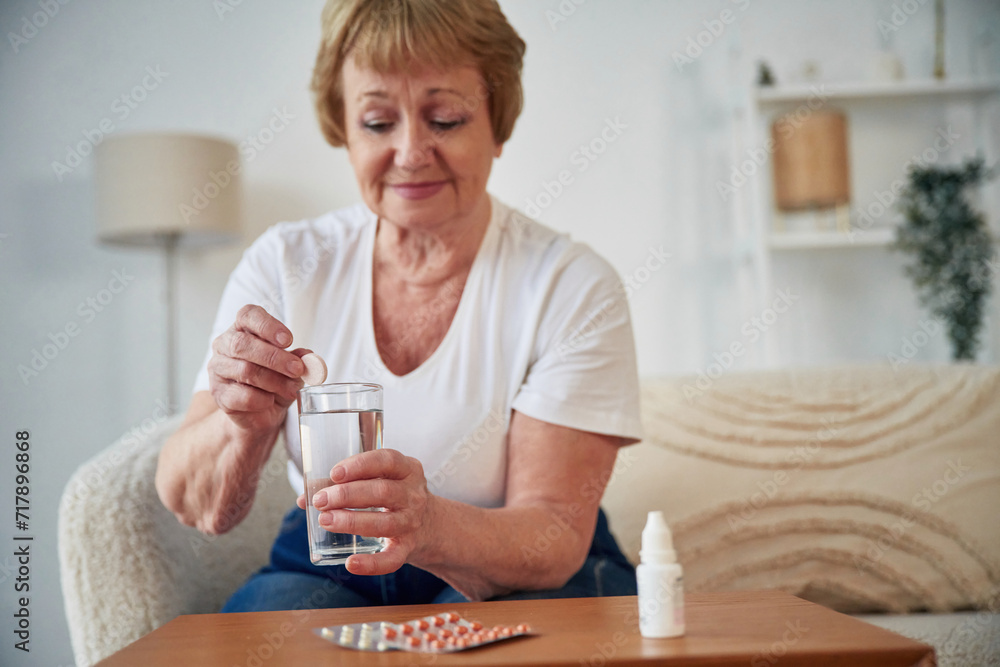 Taking the medicine, conception of illness. Senior elderly woman is at home in the living room Taking the medicine, conception of illness. Senior elderly woman is at home in the living room