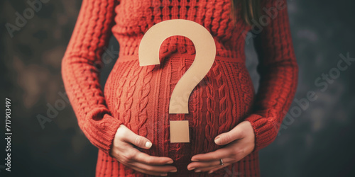 A pregnant woman holding a question mark poster.
