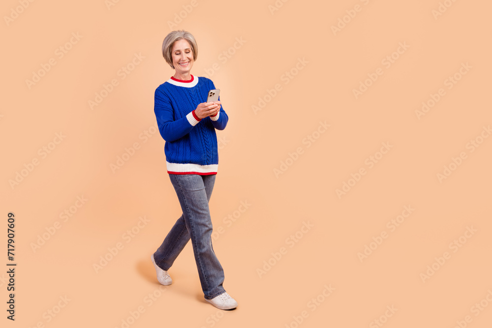Photo of adorable cheerful woman dressed stylish clothes walking using gps navigation isolated on beige color background Photo of adorable cheerful woman dressed stylish clothes walking using gps navigation isolated on beige color background