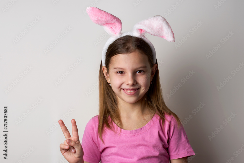 Cute girl wearing bunny ears headband posing over white background Cute girl wearing bunny ears headband posing over white background