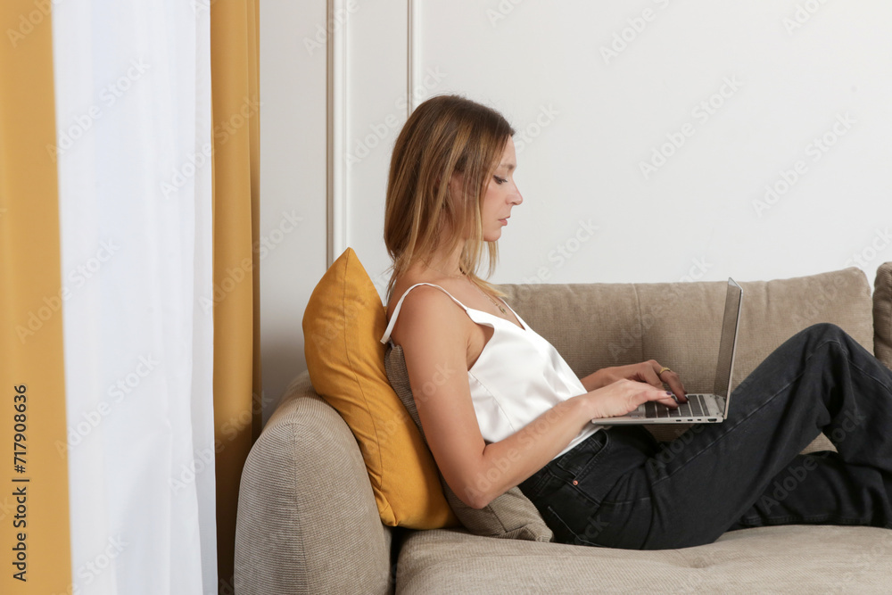 Young beautiful woman using laptop on sofa in the livingroom, working from home, internet addiction, social media, leisure time, web shopping, online education concept. Young beautiful woman using laptop on sofa in the livingroom, working from home, internet addiction, social media, leisure time, web shopping, online education concept.