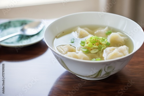 dumpling soup in a clear broth with scallions floating on top