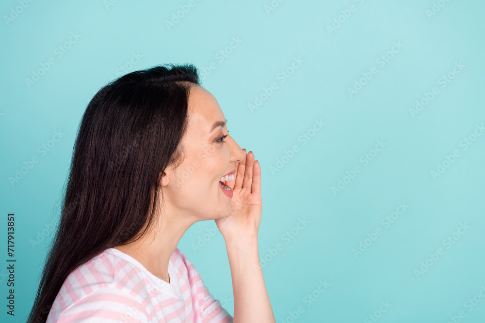 Photo of adorable excited mixed race mestizo lady dressed striped t-shirt arm mouth telling secret empty space isolated teal color background