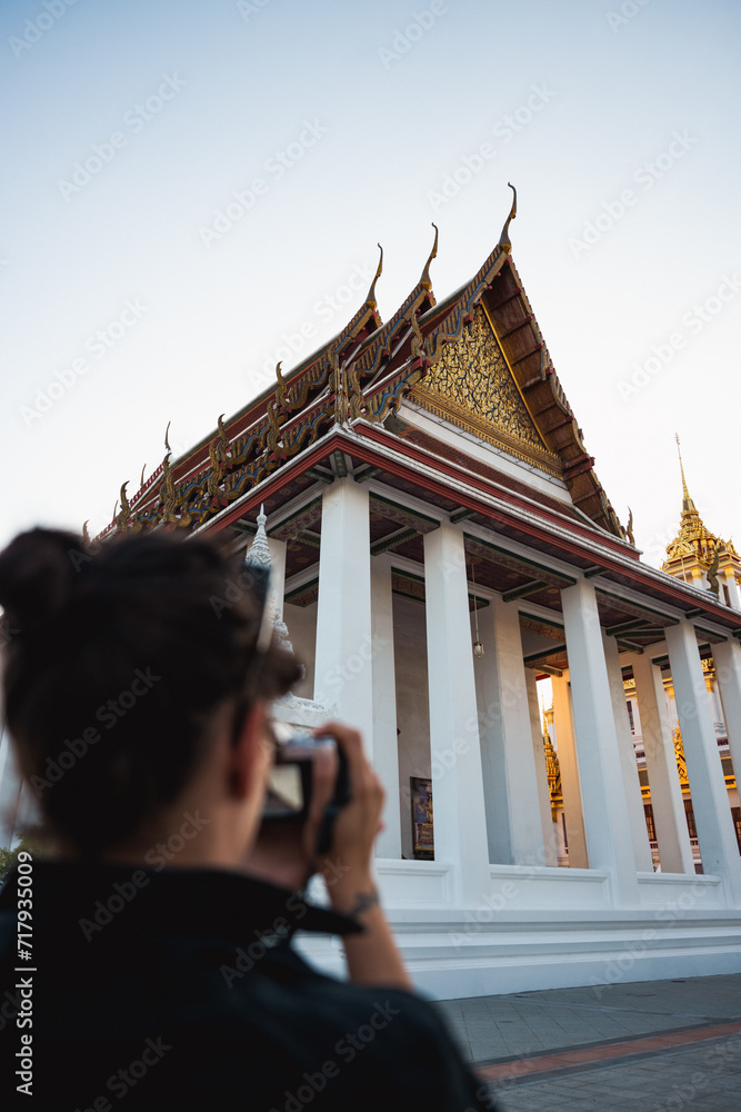 (Selective focus) A defocused tourist is taking pictures at the Wat Ratchanatdaram, a beautiful Buddhist temple that stands proud in the heart of downtown Bangkok, Thailand.