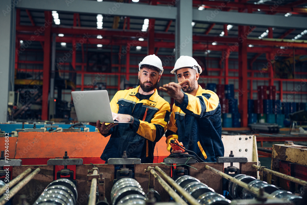 Industrial man engineer wear uniform and helmet using laptop are checking system machine at factory. Workers industrial factory. Machine maintenance technician operation concept. Industrial man engineer wear uniform and helmet using laptop are checking system machine at factory. Workers industrial factory. Machine maintenance technician operation concept.