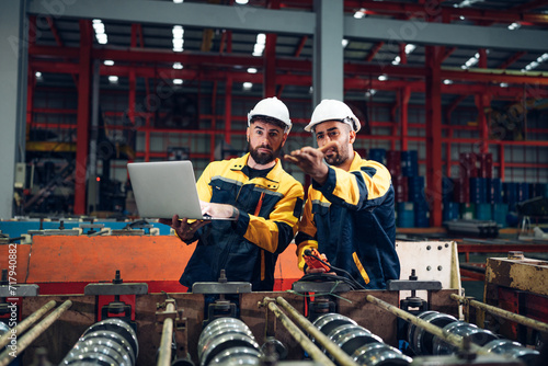 Industrial man engineer wear uniform and helmet using laptop are checking system machine at factory. Workers industrial factory. Machine maintenance technician operation concept.