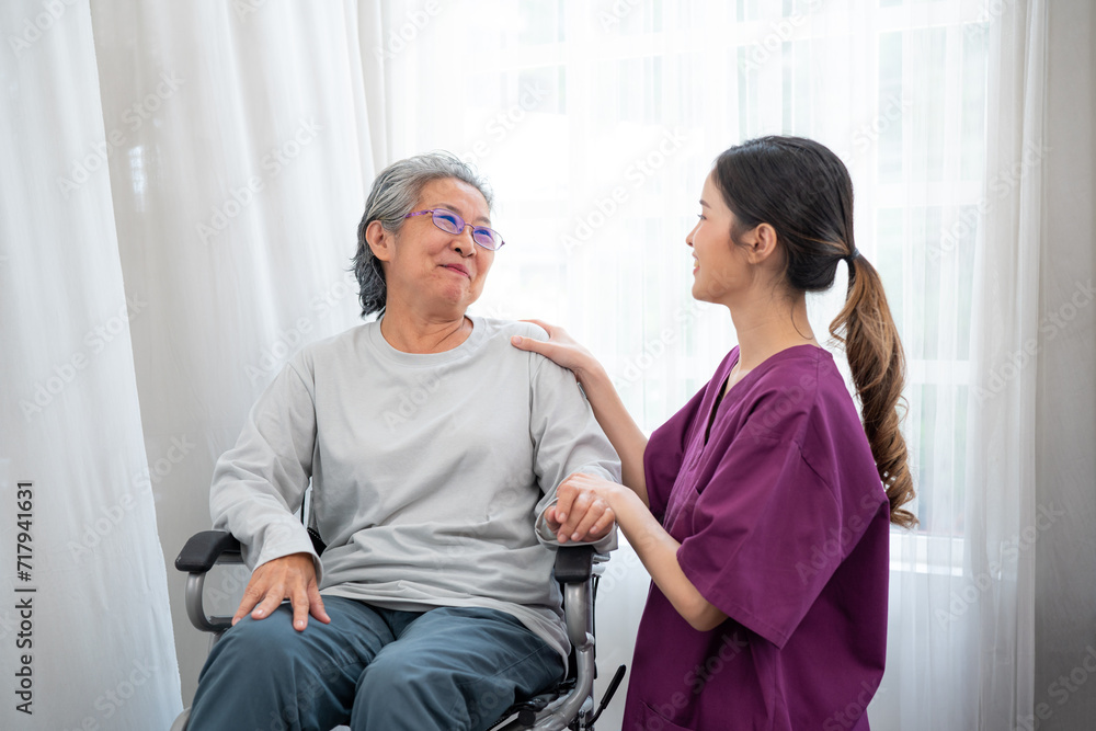 Asian young nurse taking care and talking mature female patient sitting on wheelchair in hospital. Healthcare concept. Asian young nurse taking care and talking mature female patient sitting on wheelchair in hospital. Healthcare concept.