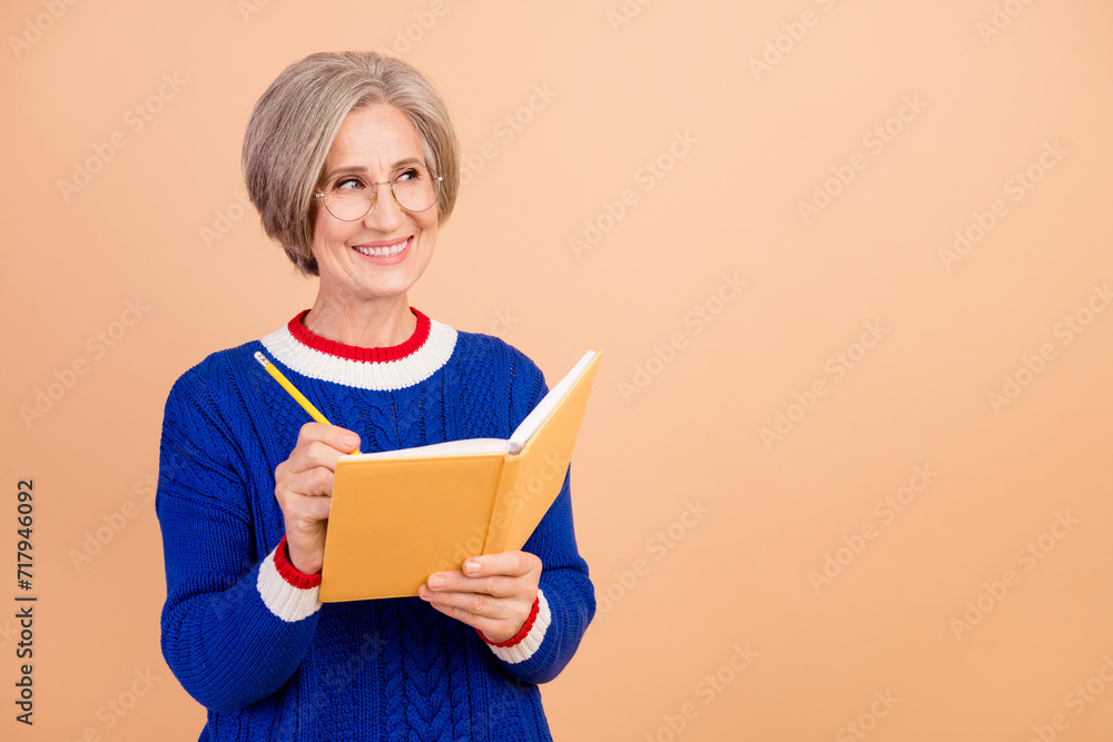 Photo of cheerful lovely senior lady hr recruiter wear blue trendy clothes hold book look empty space isolated on beige color background Photo of cheerful lovely senior lady hr recruiter wear blue trendy clothes hold book look empty space isolated on beige color background