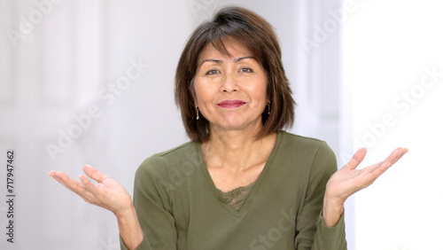 Playful attractive woman looking at camera smiling enjoying making funny hand finger gestures laughing at humor.