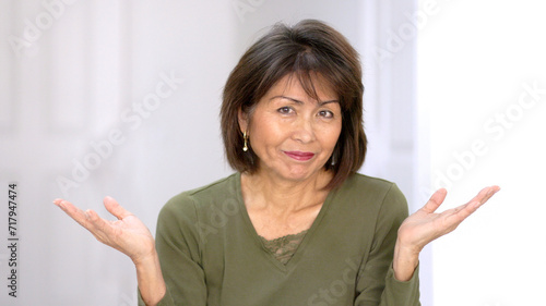 Playful attractive woman looking at camera smiling enjoying making funny hand finger gestures laughing at humor.