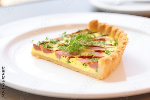whole quiche lorraine on a white plate, garnished with parsley