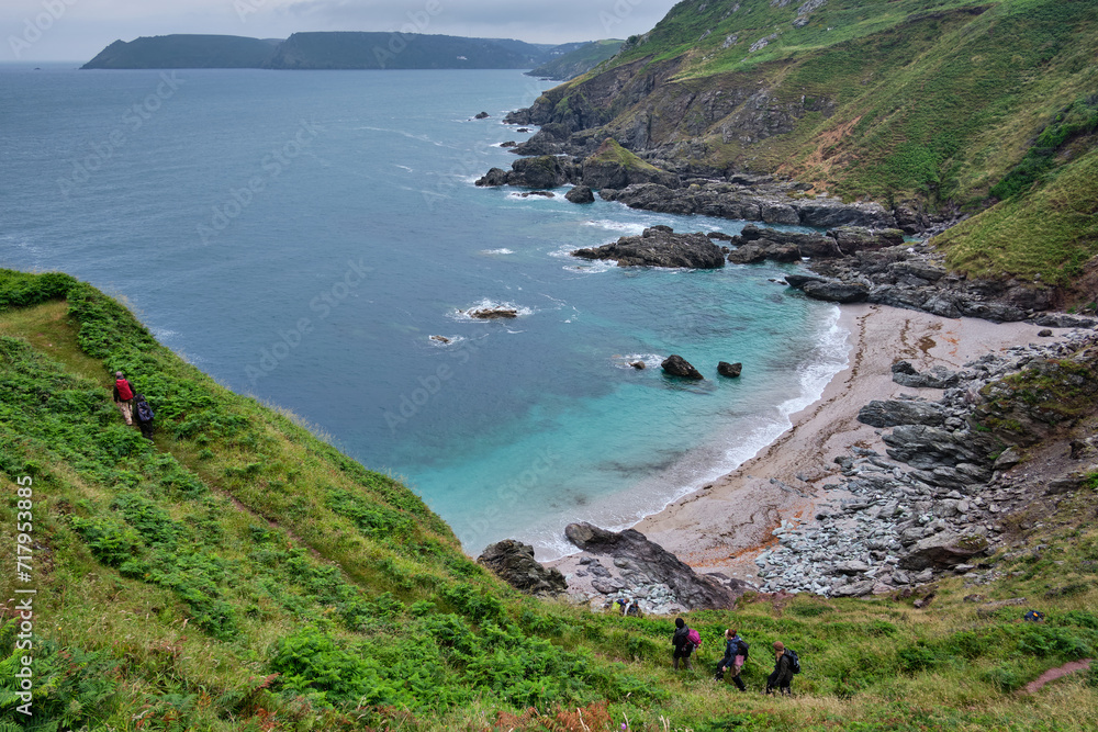 Hiker ascending from Venerick's Cove on the South West Coast Path, Devon, UK
