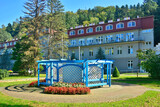 A wooden blue gazebo, located in a park in Rymanow Zdroj, Poland. Building of sanatorium in the background.
