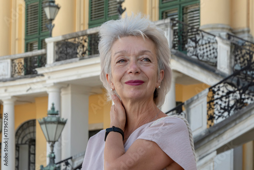 Portrait of a happy elderly gray-haired woman 65-70 years old against a background of European old architecture.