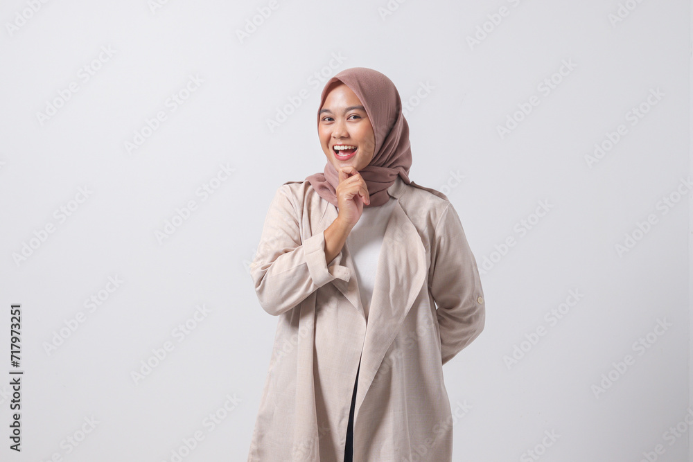 Portrait of confused Asian hijab woman in casual suit thinking with hand on chin, feeling doubt while making choice. Businesswoman concept. Isolated image on white background Portrait of confused Asian hijab woman in casual suit thinking with hand on chin, feeling doubt while making choice. Businesswoman concept. Isolated image on white background