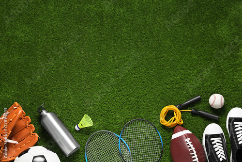 Different sports equipment on green grass, flat lay. Space for text