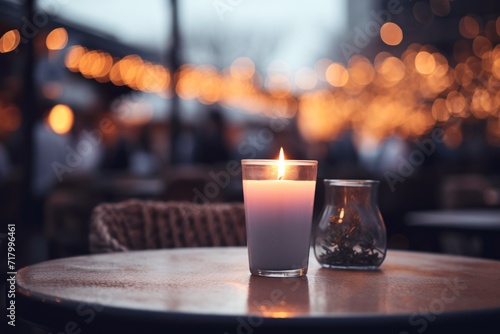 A flickering candle at an al fresco dining area during the cold season, warm ambiance, focused shot, blurred background.