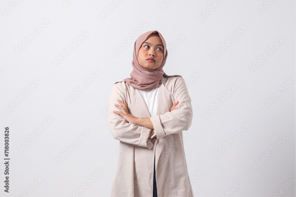 Portrait of unpleasant Asian hijab woman in casual suit keeping arms crossed and looking at camera with skeptical and distrustful look. Isolated image on white background Portrait of unpleasant Asian hijab woman in casual suit keeping arms crossed and looking at camera with skeptical and distrustful look. Isolated image on white background
