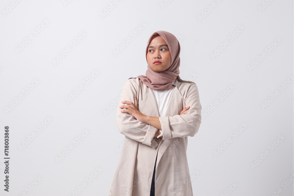 Portrait of unpleasant Asian hijab woman in casual suit keeping arms crossed and looking at camera with skeptical and distrustful look. Isolated image on white background Portrait of unpleasant Asian hijab woman in casual suit keeping arms crossed and looking at camera with skeptical and distrustful look. Isolated image on white background