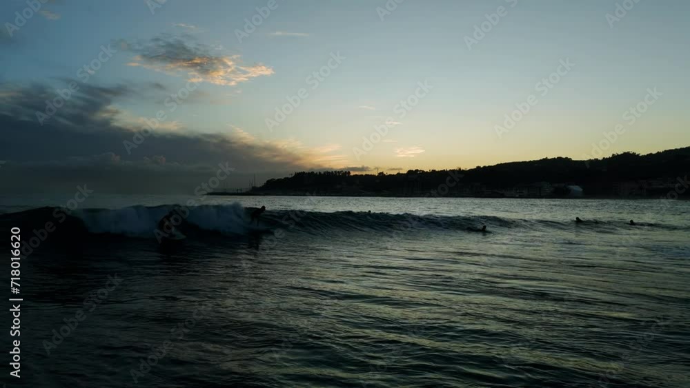 Aerial drone forward view over surfers having fun riding waves at sunset Aerial drone forward view over surfers having fun riding waves at sunset