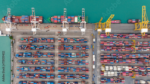 commercial port loading and unloading cargo from container ship import and export by crane for distributing goods by trailers transported to customers and dealers, aerial top view
