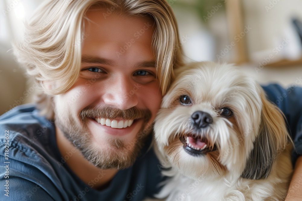 Happy blonde man hugging his shih tzu dog in a living room Happy blonde man hugging his shih tzu dog in a living room