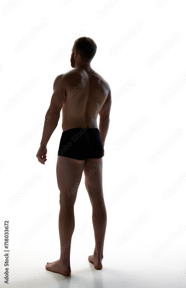 Full length back view portrait of young attractive man with perfect body curves against white studio background. Concept of natural beauty, aesthetic of body, male health, masculinity.