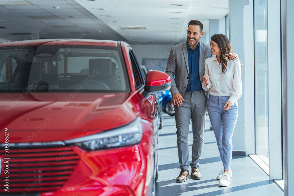 Shot of a young couple looking at cars at a car dealership. It is the one car I want! Beautiful young couple standing at the dealership choosing the car to buy Shot of a young couple looking at cars at a car dealership. It is the one car I want! Beautiful young couple standing at the dealership choosing the car to buy