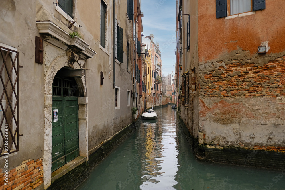 Typical narrow streets and canals between сolorful and shabby houses in Venice, Italy. 