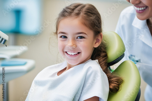 Portrait of a child being examined by a dentist. Lovely little girl smiling sitting in a dental chair. Child at the dentist. photo