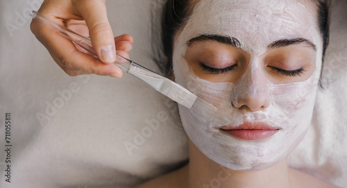 Close-up shot of a woman getting facial treatment with clay mask. Cosmetology and spa