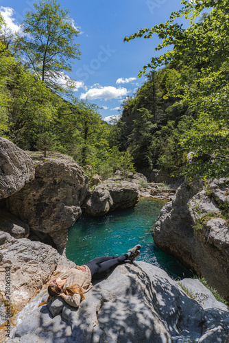 Woman lying on a rock sunbathing near a river in the Pyrenees