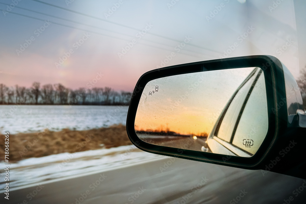 Sunset reflecting in car mirror on winter drive