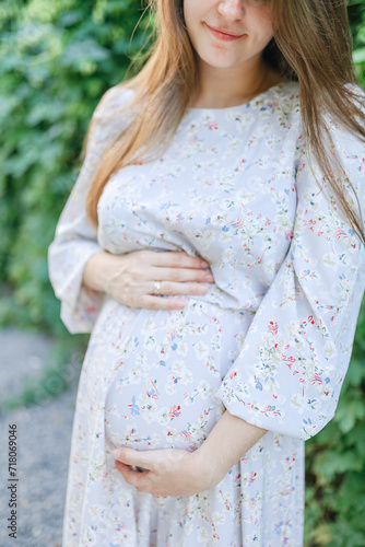 Pregnant young woman holding her belly in the park photo