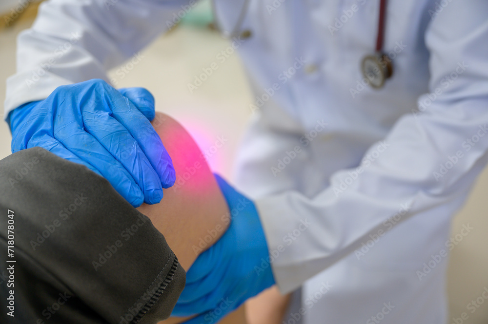 A doctor is examining the knee of a woman who has a knee injury. Foot treatment with an orthopedic surgeon will treat pain caused by running or exercising incorrectly A doctor is examining the knee of a woman who has a knee injury. Foot treatment with an orthopedic surgeon will treat pain caused by running or exercising incorrectly