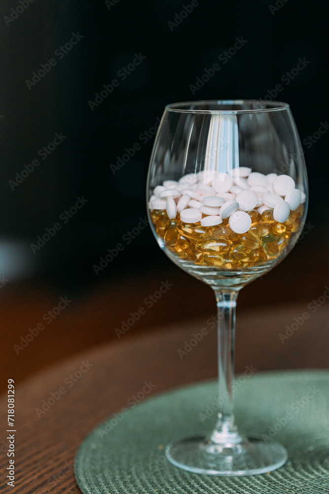 Round tablets of light pink color in a glass and transparent capsules of yellow color. Taking vitamins to improve health and well-being. Dietary . Vitamin supplements on the recommendation of a doctor Round tablets of light pink color in a glass and transparent capsules of yellow color. Taking vitamins to improve health and well-being. Dietary . Vitamin supplements on the recommendation of a doctor