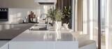 The camera zoomed in, capturing a close view of the white stylish kitchen with a cooking island, nestled within the luxurious interior of a modern apartment adorned in light colors and furnished with