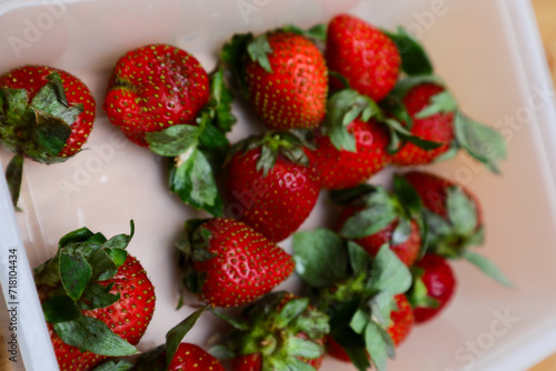 strawberries in a plastic container on a wooden table